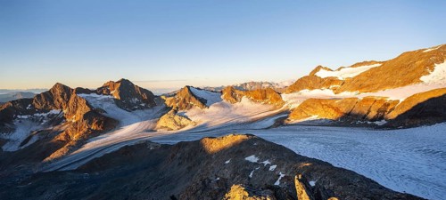 Picturesque high mountain landscape at sunrise with alpenglow, glacier and rocky mountain peaks in