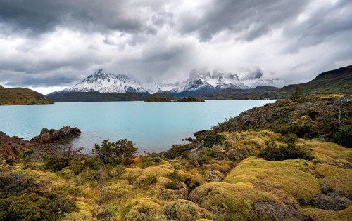 Cloudy mountain range Cuernos del Paine, shore of the blue lake Lago Pehoe in the evening light,