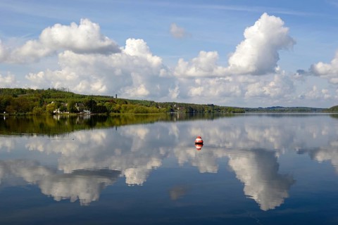 View over the Möhnesee, Möhnesee tower, red and white buoy, blue cloudy sky, reflection on the
