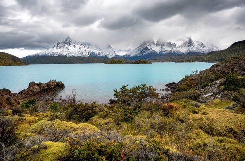 Cloudy mountain range Cuernos del Paine, shore of the blue lake Lago Pehoe in the evening light,