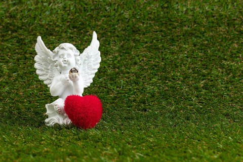 A white angel figure with a red heart on green grass