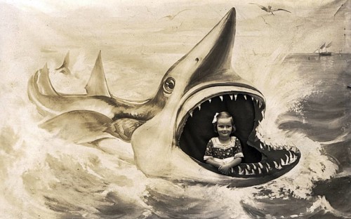 Girl posing for a photo in the painted mouth of a shark. Kitsch. ca. 1920s, location unknown