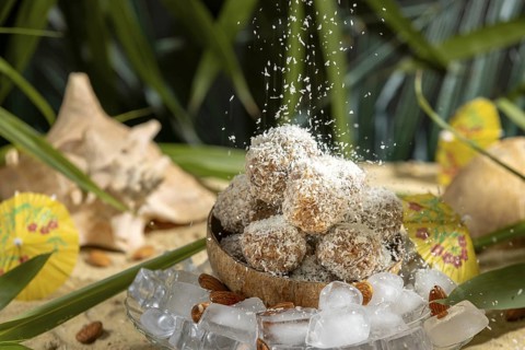 Coconut flakes fall on almond and chocolate confectionery in a coconut on ice cream with umbrellas