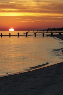 Sunset behind dilapidated fishing pier damaged by hurricanes on the Mississippi Gulf Coast in Long