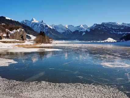 Frozen Sihlsee, reservoir, behind the snow-covered mountains Flübrig and Druesberg, Euthal, Canton