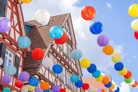 Lively balloons float above traditional half-timbered houses in a clear blue sky, Calw, Black