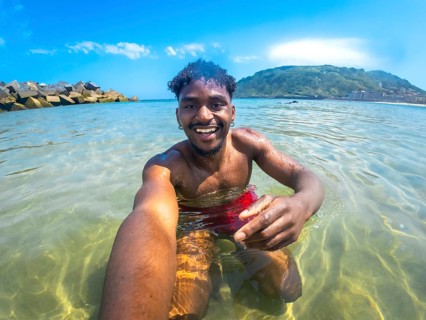 Young man enjoying a sunny summer day, capturing a joyful selfie while bathing in crystal clear sea