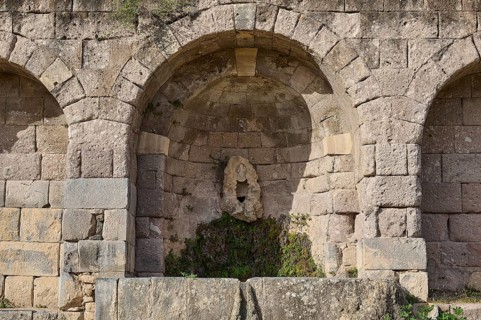 Ancient round arches with a sculpture and moss growth, arcade, lower terrace, Pan, Asklipion,