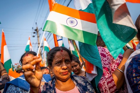 People holding Indian national flags as they take part in a rally, in soliderity with the Indian