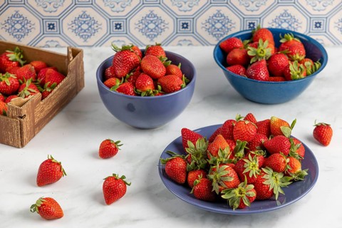 Fresh strawberries arranged in blue crockery on a marble plate
