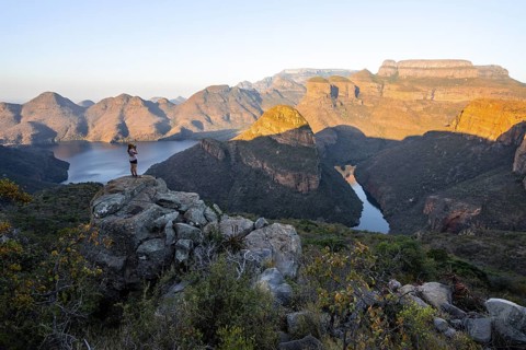 Hiker enjoying sunset at Blyde River Canyon with Three Rondawels peak, view of canyon with Blyde