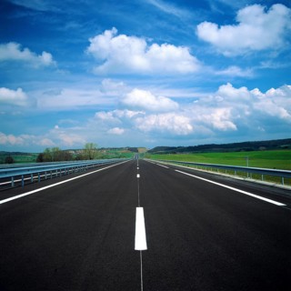 A straight stretch of a French motorway showcases smooth asphalt and clear lane markings. Lush