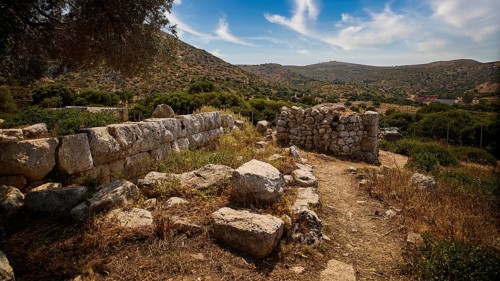 Heaven exchanged, ancient ruins in a hilly landscape with a clear blue sky and scattered clouds.