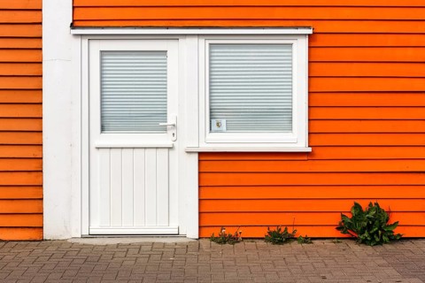 Colourful lobster shack, orange wooden façade with door and window, registry office sticker, façade