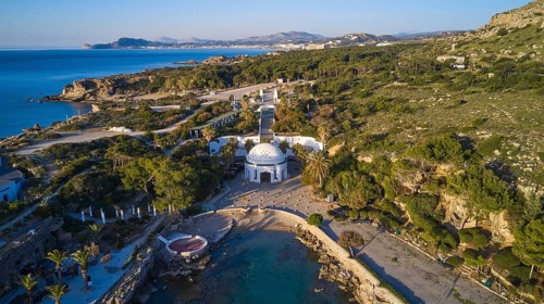Drone shot, morning light, aerial view with domed building in green coastal landscape on the blue