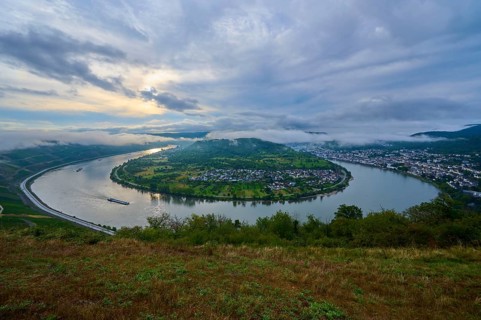 River bend at dusk with passing cargo ship and soft clouds in the sky, summer, Rhine bend Boppard,