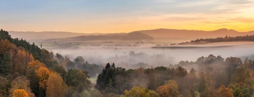 Landscape in Franconian Switzerland in autumn, view over colourful forests with morning mist at