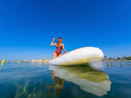 Young woman paddling on a stand up paddle board in the serene sea, soaking up the sun on a