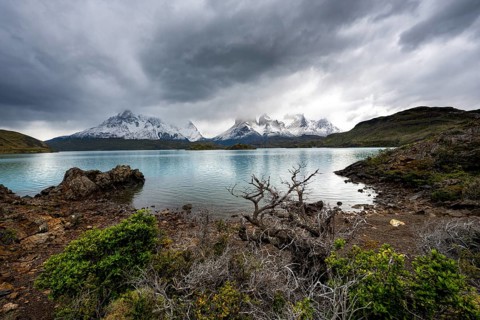 Cloudy mountain range Cuernos del Paine, shore of the blue lake Lago Pehoe in the evening light,