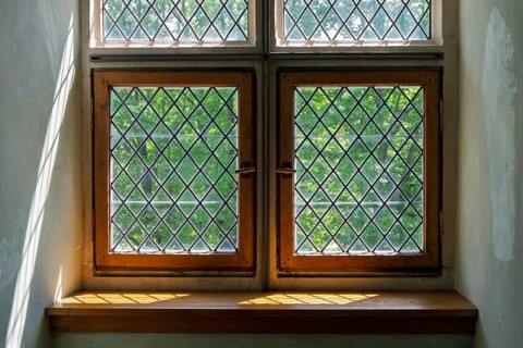 Old-fashioned windows with lattice pattern in the sunlight, wooden frames and shadows in the
