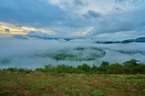River island in the mist and twilight, surrounded by mystical clouds, summer, Rhine bend Boppard,
