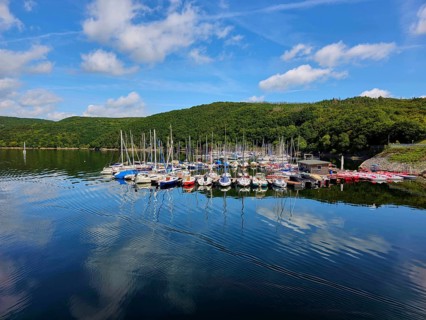 Quiet harbour with sailing boats under a blue sky and reflections in the water, surrounded by