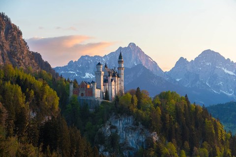 Castle in the evening light against a backdrop of snow-capped mountains, Neuschwanstein, Schwangau