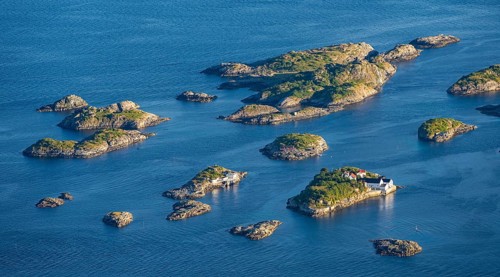 Small rocky islands with individual houses in the sea, archipelago islands, near Henningsvær,