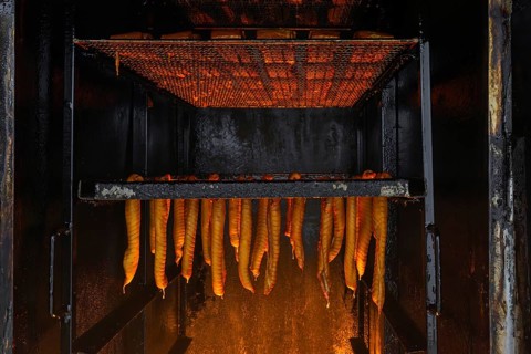 Smoking fish over beechwood fire in large metal smoker oven on the island Usedom in the Baltic Sea,