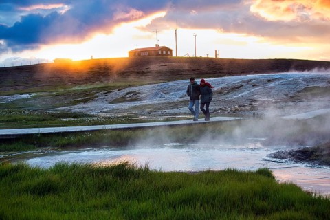 Walker on wooden path, sulphur vapour, geothermal area Hveravellir, sunset, icelandic highlands,