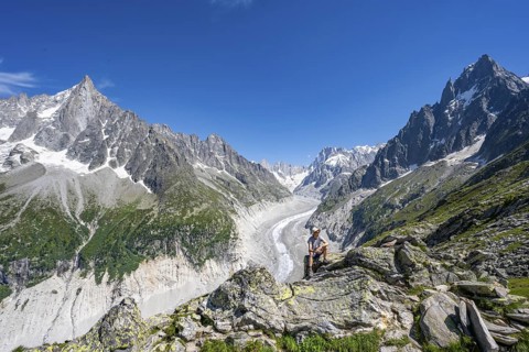 Picturesque mountain landscape with imposing mountain peaks and glaciers, mountaineer on hiking