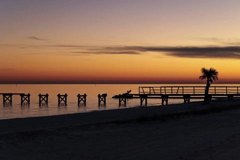 Sunset behind dilapidated fishing pier damaged by hurricanes on the Mississippi Gulf Coast in Long
