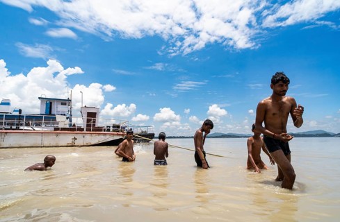 People bathe in the Brahmaputra River to seek relief from the intense summer heat in Guwahati,