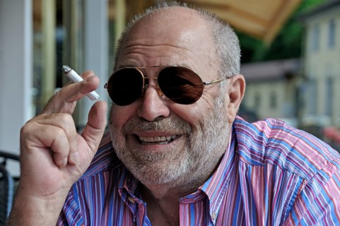 Portrait of a smiling elderly gentleman with a beard, sunglasses and a cigarette in his hand,