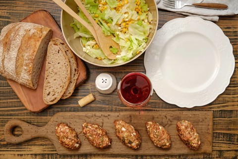 A hearty meal is prepared with freshly made meat patties, a vibrant salad with corn and greens, and