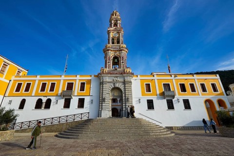 Historic building with baroque church tower and people on a square under blue sky, Holy Week,