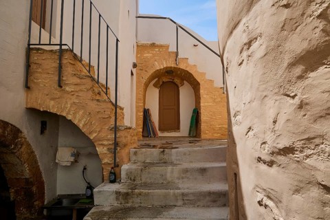 Historic courtyard with stairs, stone arches and wooden doors in the sunlight, Monastery, Moni