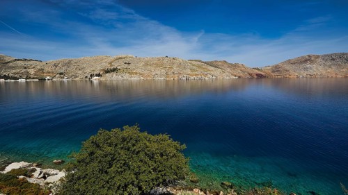 Clear bay surrounded by rocky hills under a blue sky, Bay of Emporio, Emporio, Symi, Dodecanese,