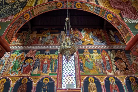 Artfully designed church interior with icons and large murals around a window, Church of the