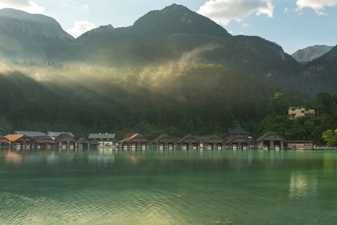 Mystical morning at Königssee in Schönau with boathouses. Sunrise and beautiful wafts of mist over