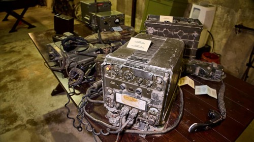 A pile of antique radios on a dark wooden table in a bunker, War Museum, Military Museum, Tunnel