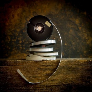 Stacked film reels rest on a worn wooden surface, highlighting the charm of vintage cinema. The