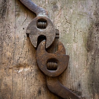 Two vintage adjustable wrenches lie closely on a rustic wooden surface, highlighting their unique