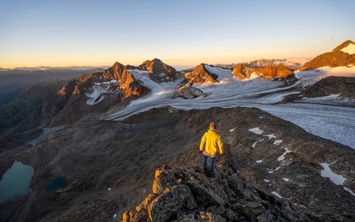 Mountaineers in front of a picturesque high mountain landscape at sunrise with alpenglow, blue