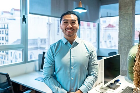 Portrait of a smiling asian businessman standing in a bright, modern office, conveying confidence