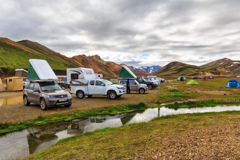 Off-road vehicle with roof tent, camping site in Landmannalaugar, Icelandic highlands, rain clouds,