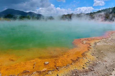 A steaming hot spring with an orange-coloured rock edge, Champagne Pool thermal lake, Wai-O-Tapu