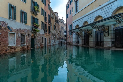 Calm water reflecting colorful buildings along a canal in venice, italy, during acqua alta, or high