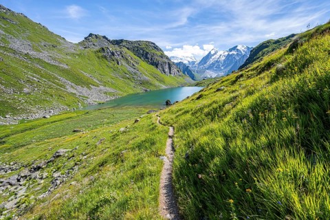 Hiking trail in a picturesque mountain landscape, view of the Lac du Louvie mountain lake and