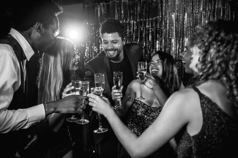 Happy friends are toasting with champagne flutes, enjoying nightlife together at a glamorous party